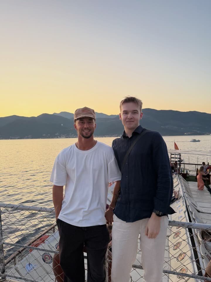 Brendan and a friend on a boat at sunset in Montenegro